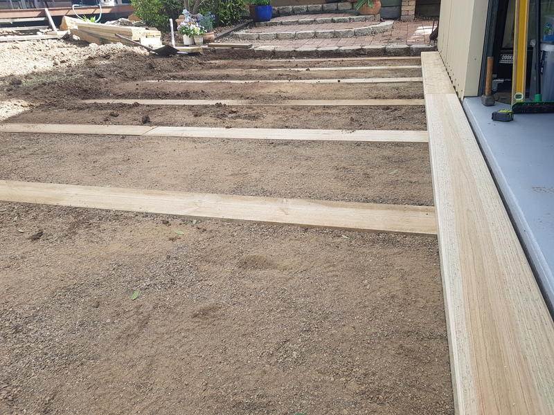 Backyard showing dirt and wooden planks ready for path creation