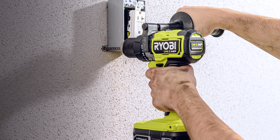 Hand with RYOBI drill, securing a powerpoint into plasterboard