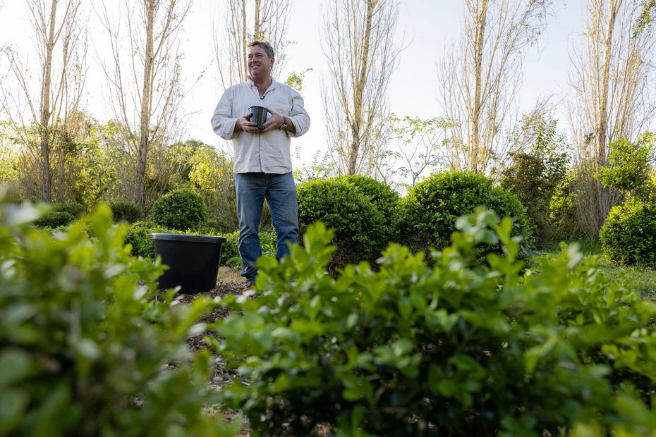 Jason Hodges stands in the garden holding a plant pot