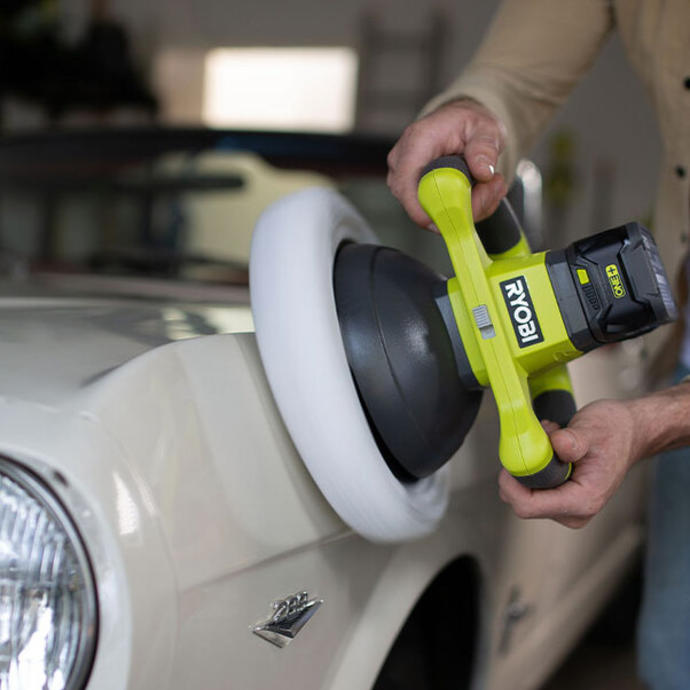 A man uses a Ryobi buffing tool to polish a car