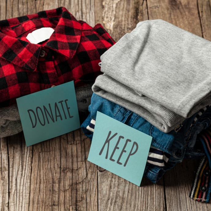 Two piles of folded clothes marked as keep and donate