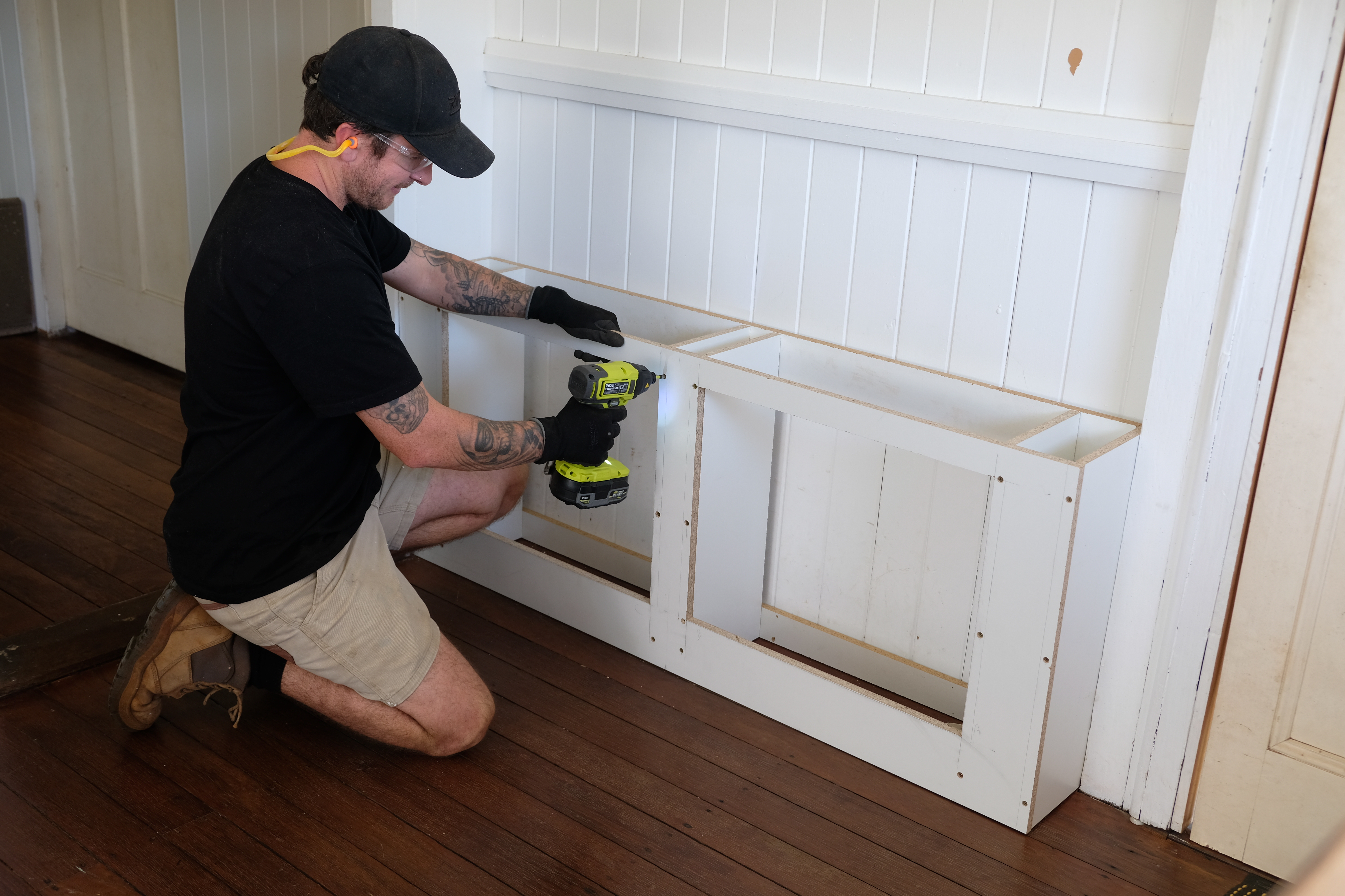 Jake uses a RYOBI impact driver to assemble the DIY shoe cabinet frame and fix it to the wall.