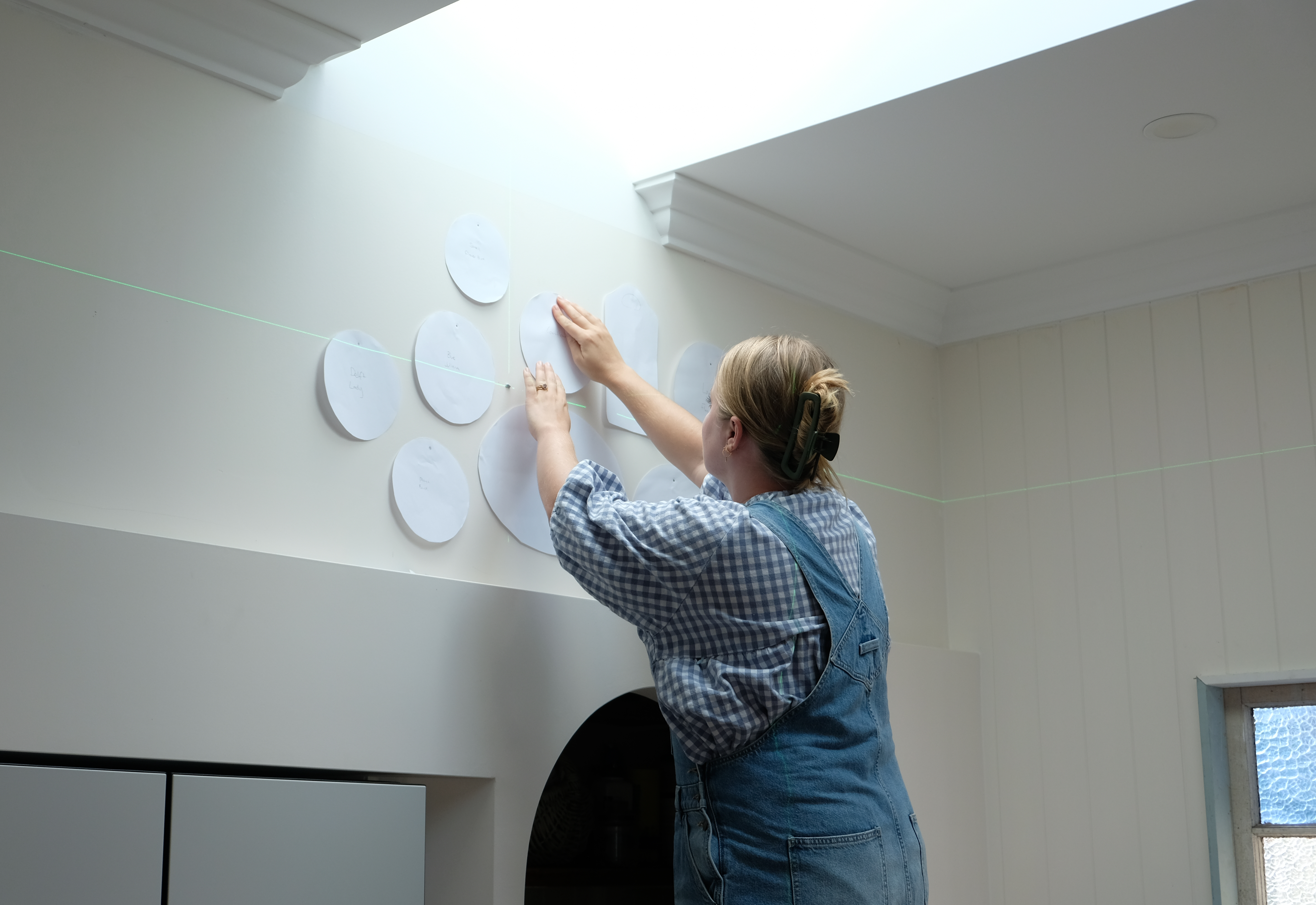 Brooke uses Blu Tac to position the paper templates on the wall and setup the gallery layout.