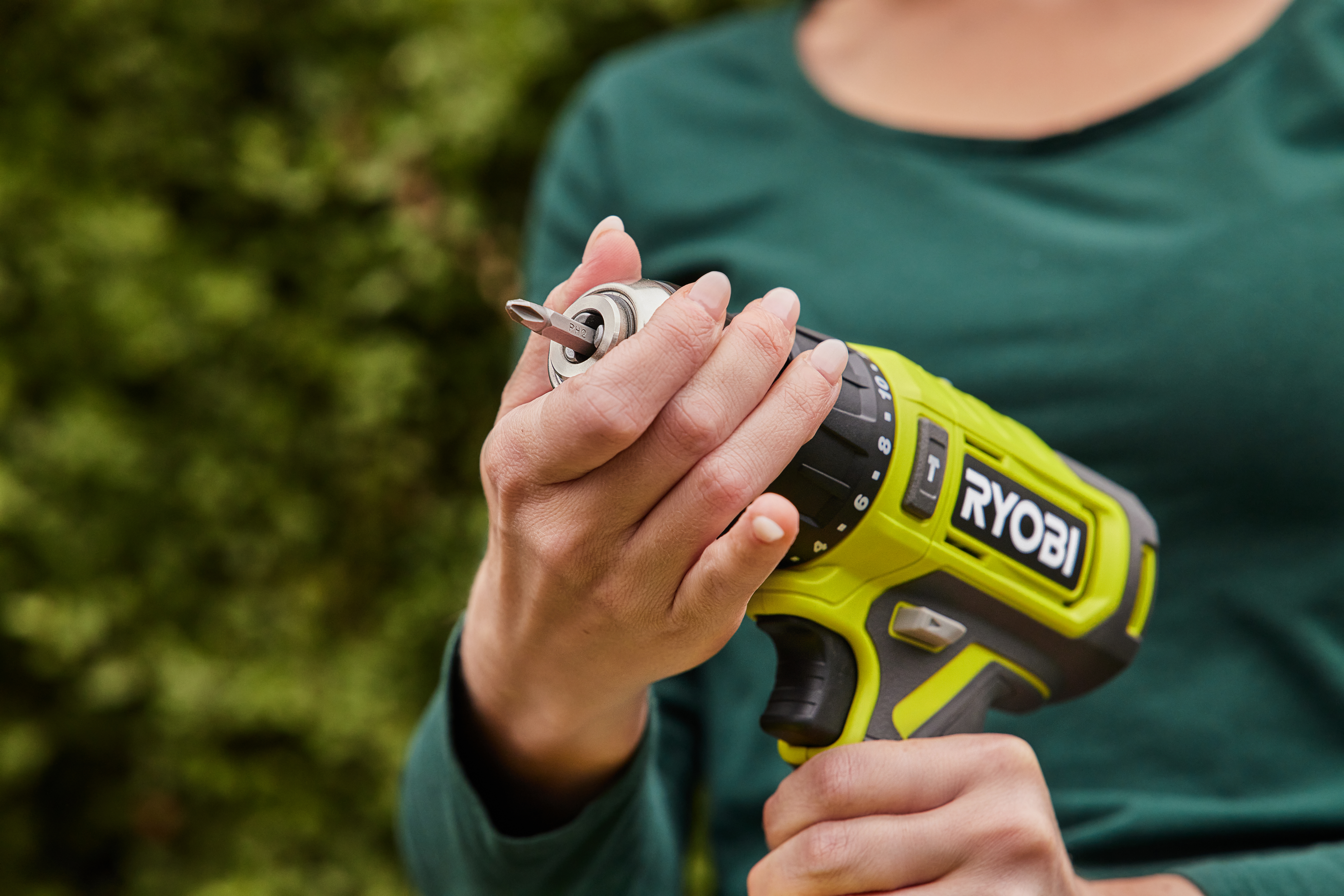 A woman holds a RYOBI Drill Driver, getting ready to do some DIY in her backyard