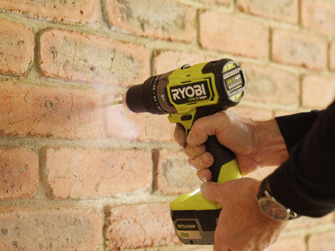 Person drilling into brick wall with RYOBI drill. 