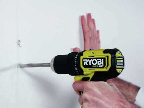 Close up of drilling into a white wall with RYOBI drill.