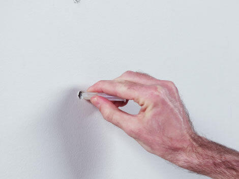 Hand inserting LINK storage wall anchors into white wall.