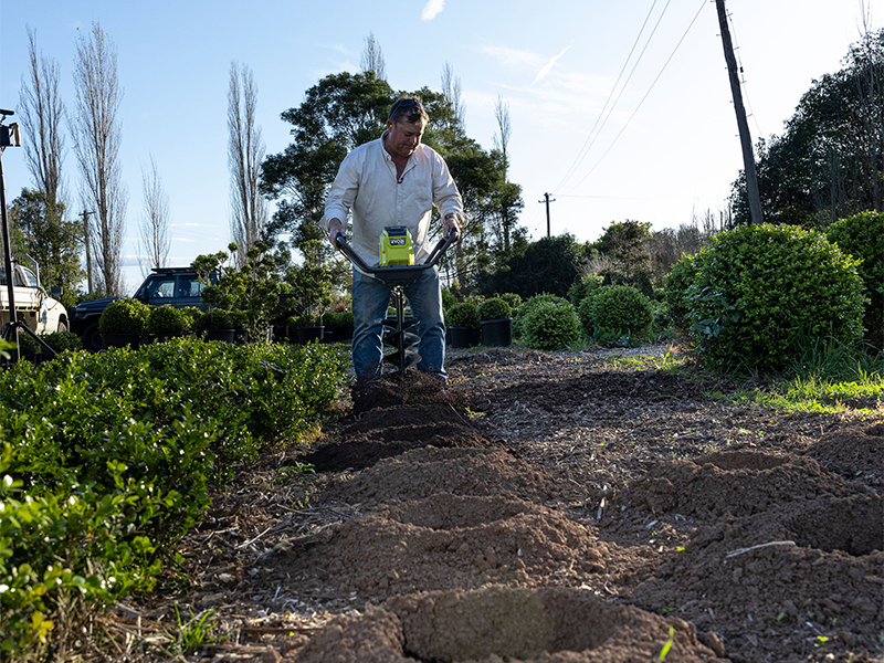 Jason Hodges using a RYOBI digging tool to create holes for planting